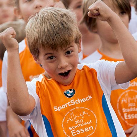 Ein Junge bei einem Stadtlauf jubelt und streckt die Arme nach oben