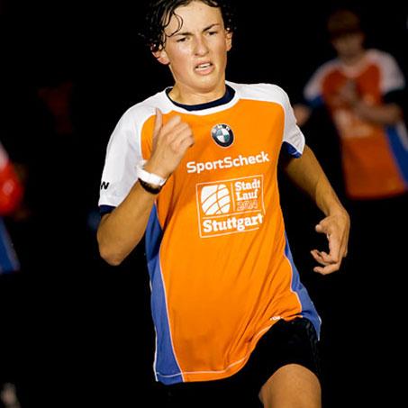 Ein Junge läuft bei einem Stadtlauf mit und schaut angestrengt