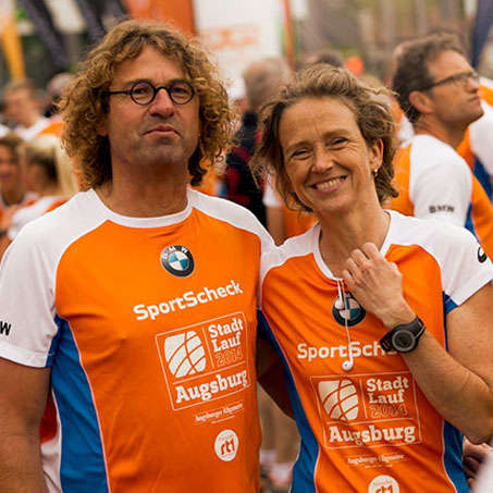Ein Mann und eine Frau in SportScheck Stadtlauf Trikots kurz vor dem Augsburger Stadtlauf Start.
