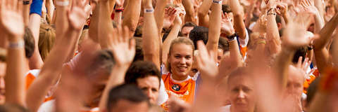Viele Teilnehmer strecken ihre Arme in die Luft, eine Läuferin schaut direkt in die Kamera beim Stadtlauf in Braunschweig.