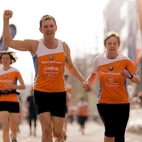 Ein Mann und eine Frau laufen Hand in Hand Richtung Ziellinie beim Stadtlauf Chemnitz.