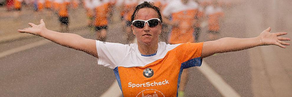 Eine L&auml;uferin streckt die Arme seitlich vom K&ouml;rper weg w&auml;hrend eines Dresden Stadtlaufs bei Regen.