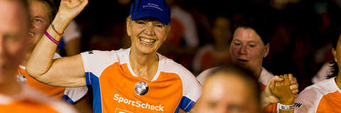 Eine Frau streckt den Arm in die Höhe und lächelt beim Zieleinlauf vom Stadtlauf Hannover.