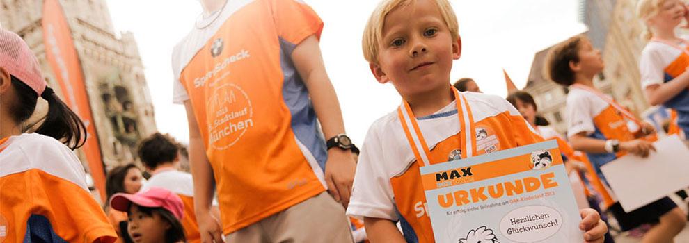 Ein Junge hält stolz seine Teilnehmer-Urkunde für den Münchener Stadtlauf in die Kamera.