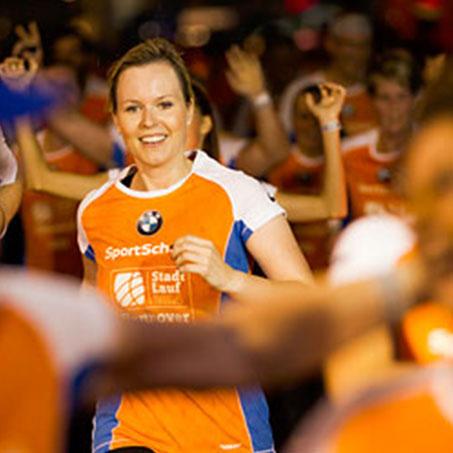 Eine Frau läuft beim Stadtlauf Hannover lächelnd auf der Zielgerade.