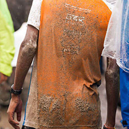 Ein Läufer beim Stadtlauf München steht mit dem Rücken zur Kamera. Er trägt ein schlammbespritztes Laufshirt.