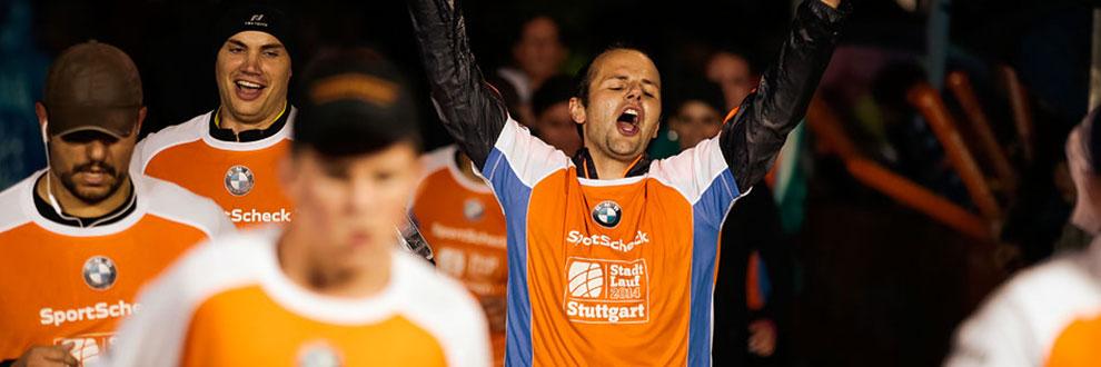 Eine Gruppe L&auml;ufer l&auml;uft bei einem Stadtlauf mit und jubelt