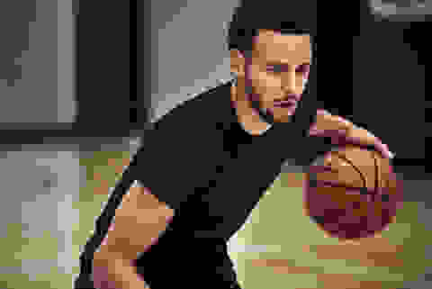Steph Curry trainiert Basketball in einer Basketball-Halle und trägt dabei ein Shirt der Under Armour Curry Kollektion.