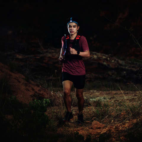 Ein Trailrunner während des Laufens von vorne im Dunkeln fotografiert.