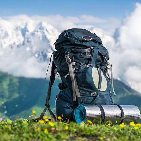 Ein vollgepackter Rucksack steht vor einem Bergpanorama.
