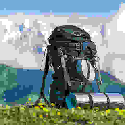 Ein vollgepackter Rucksack steht vor einem Bergpanorama.