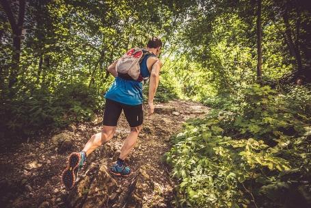 Ein Trailrunner läuft in einem Wald einen Berg nach oben