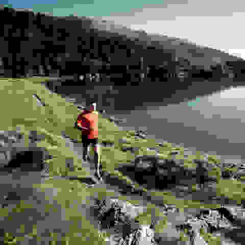 Ein Trailrunner läuft an einem Bergsee entlang.