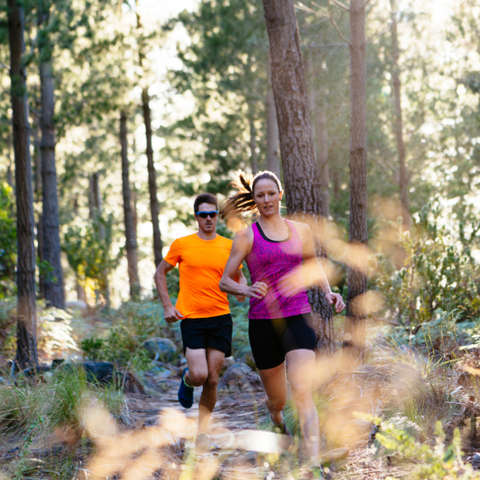 Ein Mann und eine Frau beim Trailrunning im Wald. 