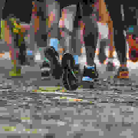 Läufer laufen auf einem Feldweg nebeneinander her. Zu sehen sind die Unterschenkel und Füße, die in unterschiedlichen Laufschuhmodellen stecken.