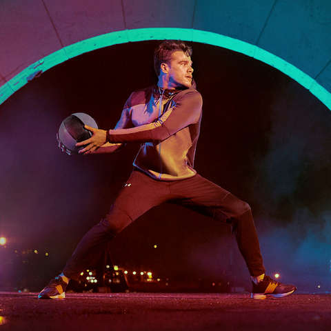 Mann trainiert im Freien mit einem Medizinball und trägt Under Armour Coldgear Sportkleidung