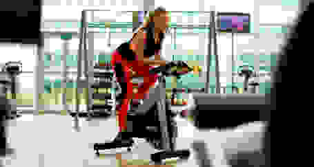 Eine Frau trainiert im Fitnessstudio auf einem Fahrrad-Ergometer.