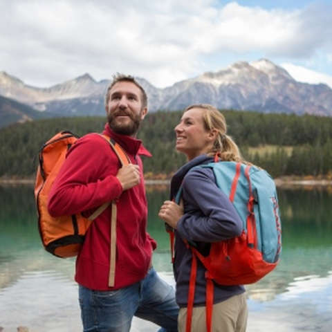 Ein Mann und eine Frau stehen in Kanada vor einem herrlichen See. Im Hintergrund ist ein Bergpanorama zu sehen.