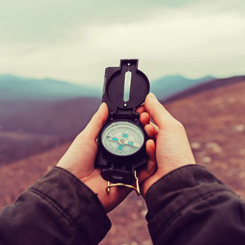 Ein Wanderer orientiert sich in den Bergen mit Hilfe eines Kompasses
