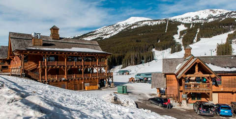 Ein großes Holzhaus umgeben von Schnee. Kanada ist ideal für Wintersportler.