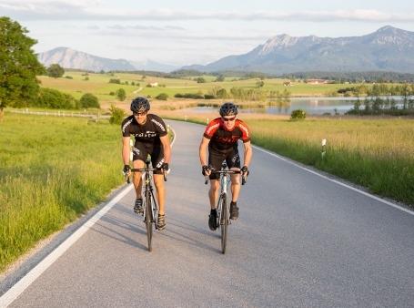 Zwei Radfahrer fahren durch eine grüne bergige Natur