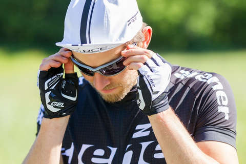 Ein Radfahrer in Nahaufnahme. Er trägt einen Fahrradhelm und Fahrradtrikot von ZIENER in schwarz/weiß. Dazu passende ZIENER Fahrradhandschuhe und eine Sonnenbrille.