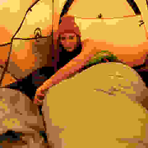 Eine Frau liegt im Zelt in einem warmen Daunenschlafsack