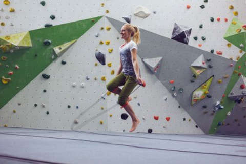 Eine Frau wärmt sich mit Seilspringen in einer Boulderhalle auf. Bild 2