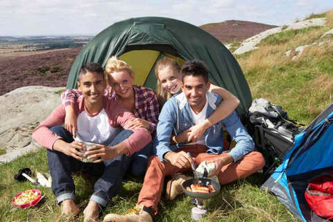 Eine Gruppe Camper beim Essen vor ihrem Zelt.