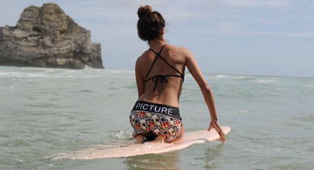 Eine Frau kniet im Wasser auf einem Surfbrett.
