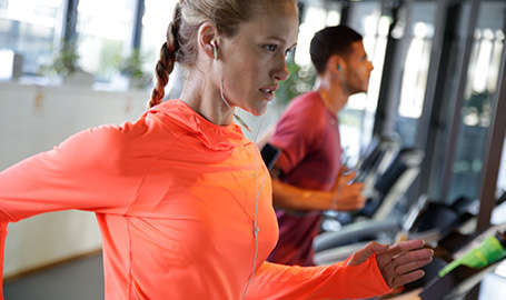 Eine Frau trainiert im Fitnessstudio auf einem Laufband.