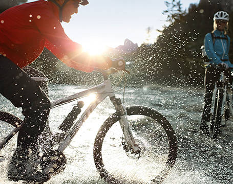 Ein Radfahrer fährt durch eine große Pfütze.