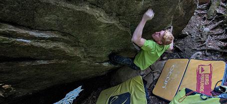 Fabian Schröder beim Outdoor Bouldern. Auf dem Boden liegen Crashpads.
