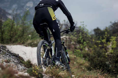 Ein Radfahrer auf einem Mountainbike fährt in einer Waldlandschaft mit hochwertig Fahrradausrüstung.