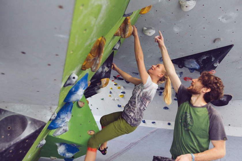 Ein Mann und eine Frau bouldern gemeinsam in einer Boulderhalle