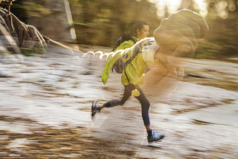 Eine Trailrunnerin mit hoher Geschwindigkeit fotografiert. Darüber gelegt ein 2. Bild, welches eine Sportuhr am Handgelenk zeigt.
