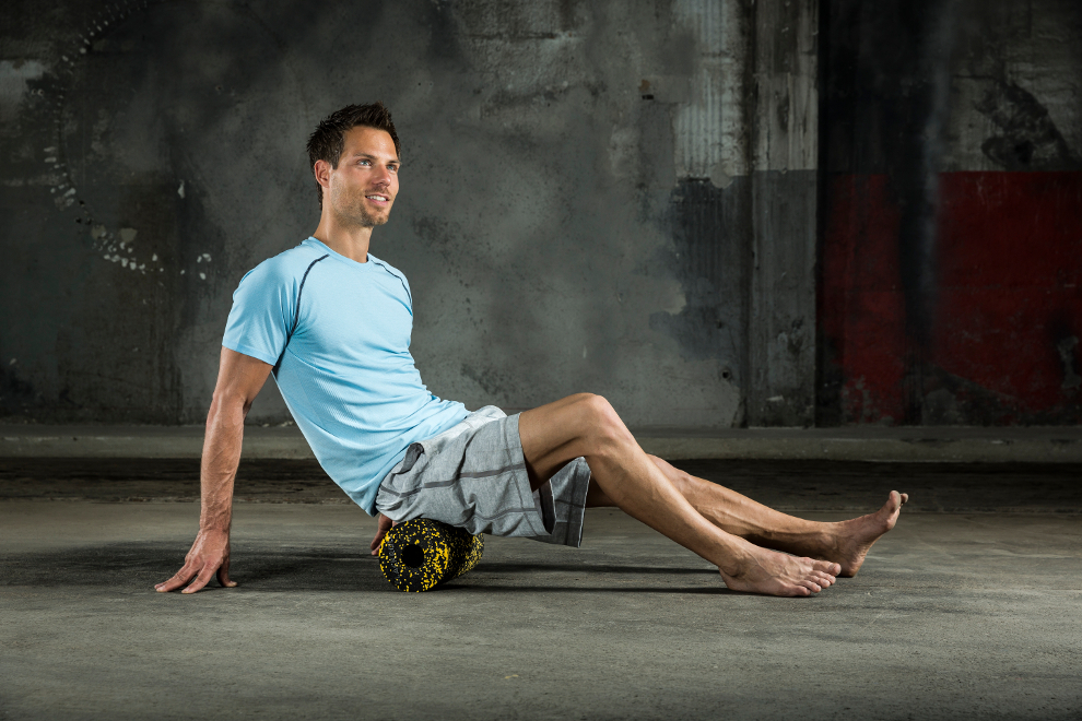 Ein Mann trainiert sein Ges&auml;&szlig; mit einer Faszienrolle von Blackroll.