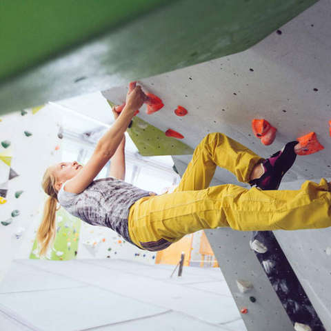 Eine Frau demonstriert in einer Kletterhalt die Technik Überhang klettern.