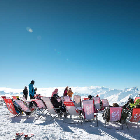 Eine Gruppe Skifahrer macht in Liegestühlen Pause.