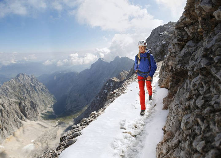 Eine Frau mit Helm wandert in einer winterlichen alpinen Landschaft