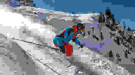 Ein Skifahrer fährt mit Skihelm eine steile Piste hinab.