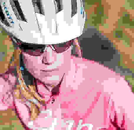 Eine Frau in der Nahaufnahme. Sie trägt eine Sportbrille und einen weißen Fahrradhelm der Marke Scott.