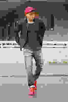 Ein Mann mit Destroyed Jeans geht eine Straße entlang. Zur Jeanshose trägt er rote Schuhe und eine schwarze Jacke.