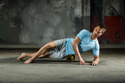 Ein Mann trainiert mit einer Blackroll seine Hüftmuskulatur.