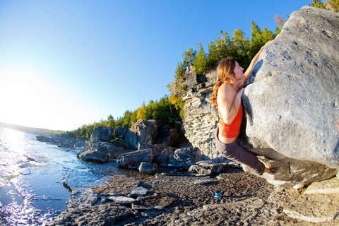 Eine Frau klettert an einem niedrigen Felsen entlang.