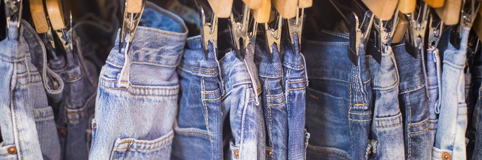 Diverse Jeanshosen auf Kleiderbügeln.