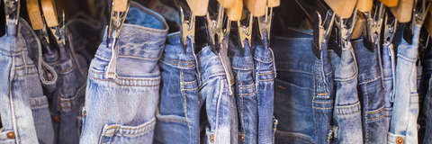 Diverse Jeanshosen für Damen auf Kleiderbügeln nebeneinander aufgehängt.