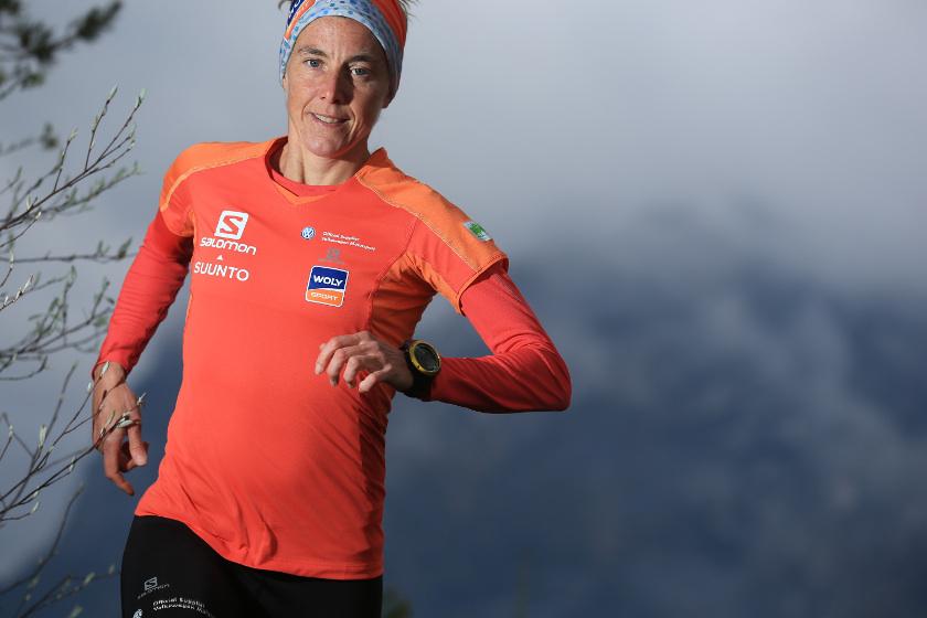 Läuferin in einem orangenen Sport-Shirt läuft durch die Landschaft