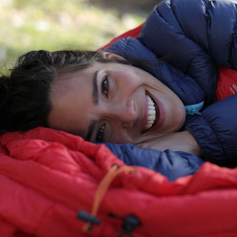 Eine Frau liegt im Freien in einem warmen Schlafsack