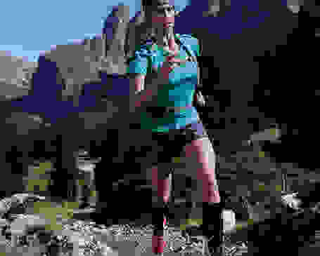 Eine Frau läuft einen Bergpfad hinauf. Dabei trägt sie kniehohe Kompressionssocken.